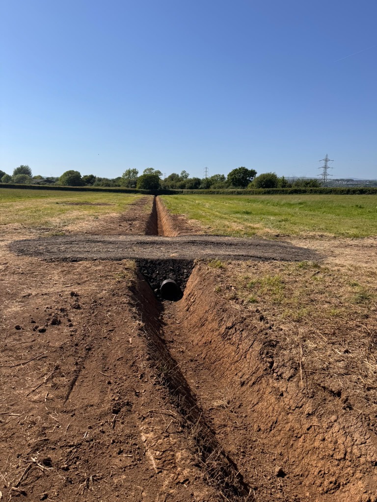 Field drainage ditch with a pipe beneath an access crossing
