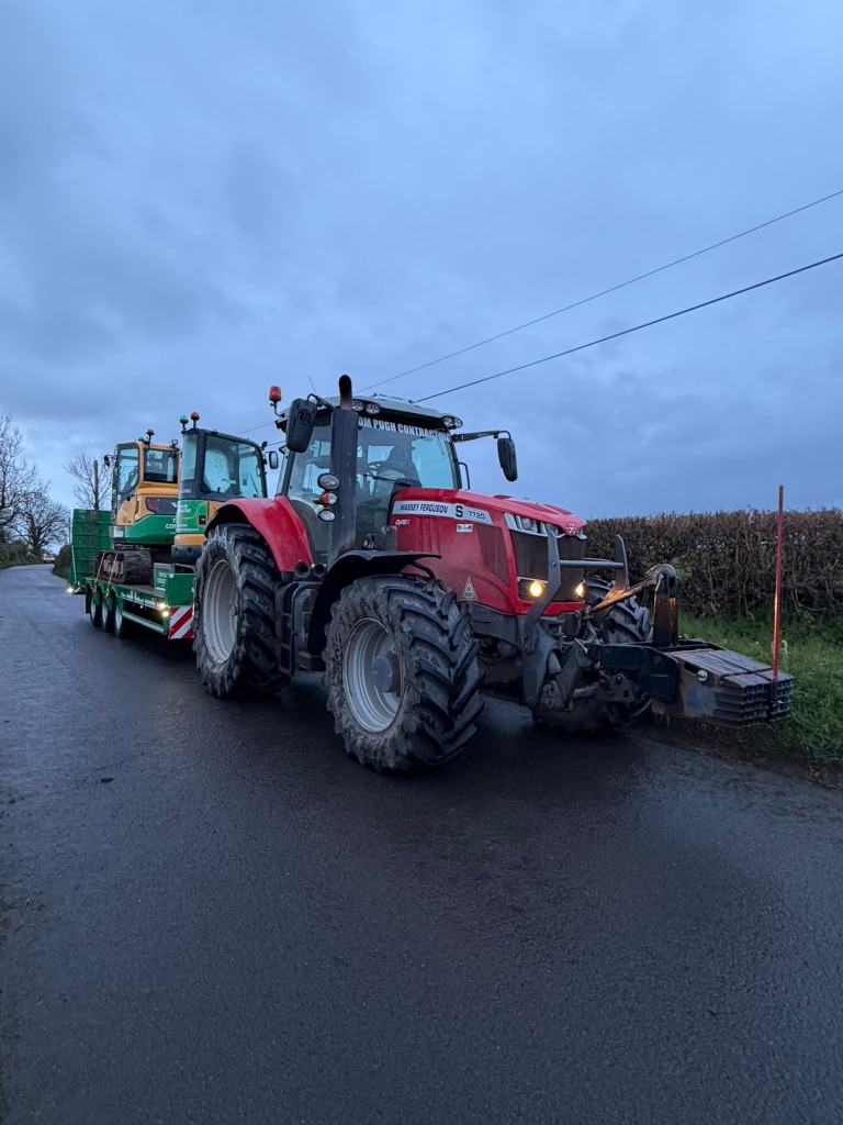 Tractor transporting an excavator on a rural road